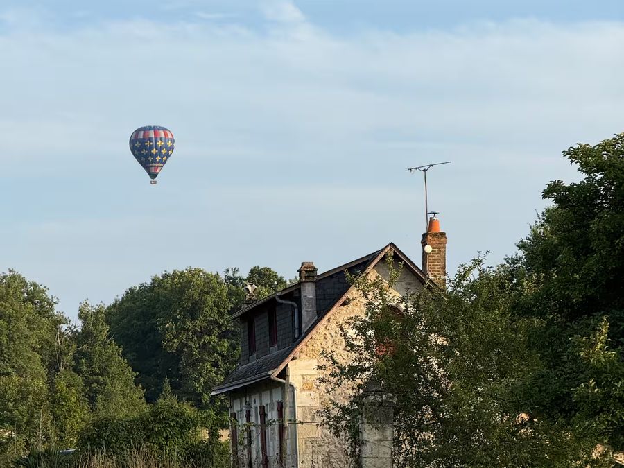 Une montgolfière passe au-dessus de la maison au petit matin